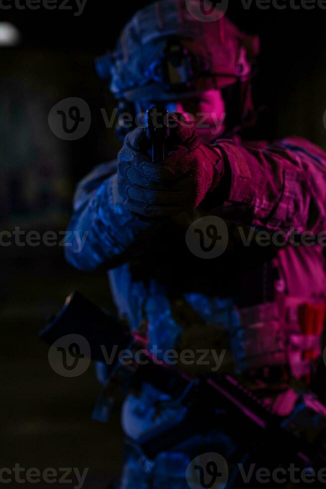 Soldier of army elite forces, special security service fighter with hidden behind mask and glasses face, in helmet and load carriage system, aiming with service pistol low key. photo