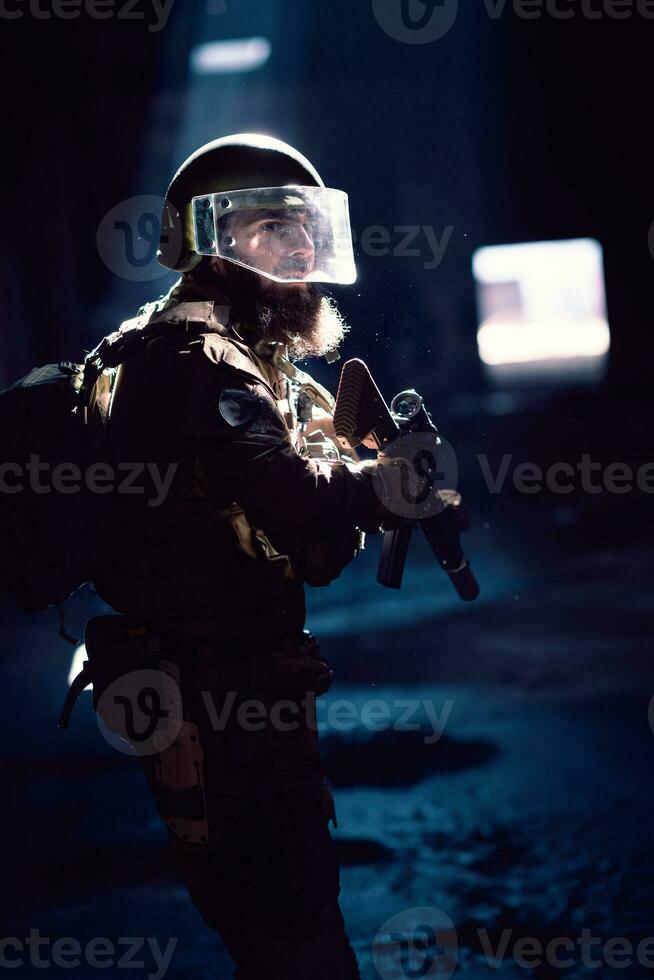 Army soldier in Combat Uniforms with an assault rifle and combat helmet night mission dark background. Blue and purple gel light effect. photo