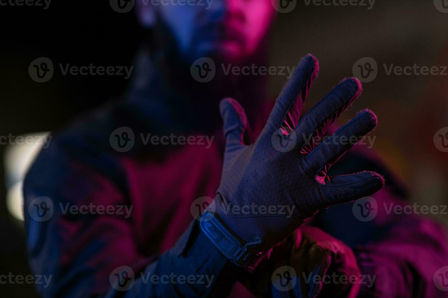 Photo of a fully equipped soldier in black armor tactical vest and gloves standing on black background closeup front view.