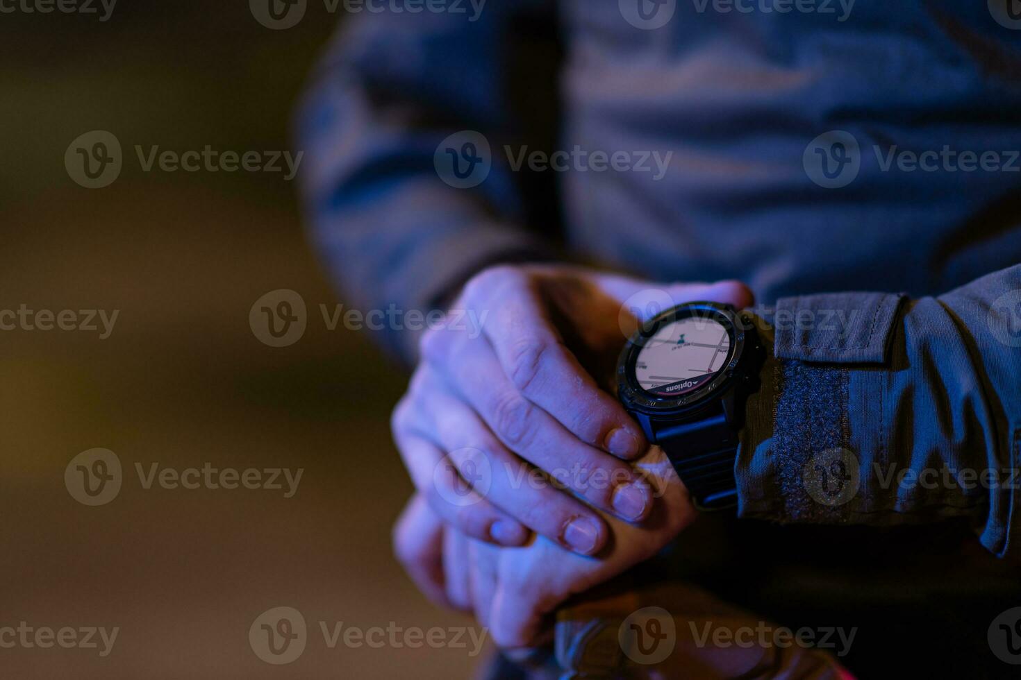 Modern warfare soldier checking navigation, time and other information on a smartwatch. Dark night black background. photo