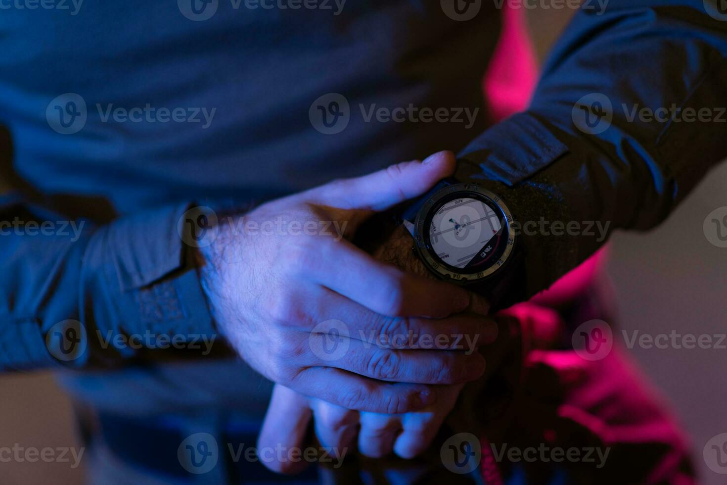 Modern warfare soldier checking navigation, time and other information on a smartwatch. Dark night black background. photo