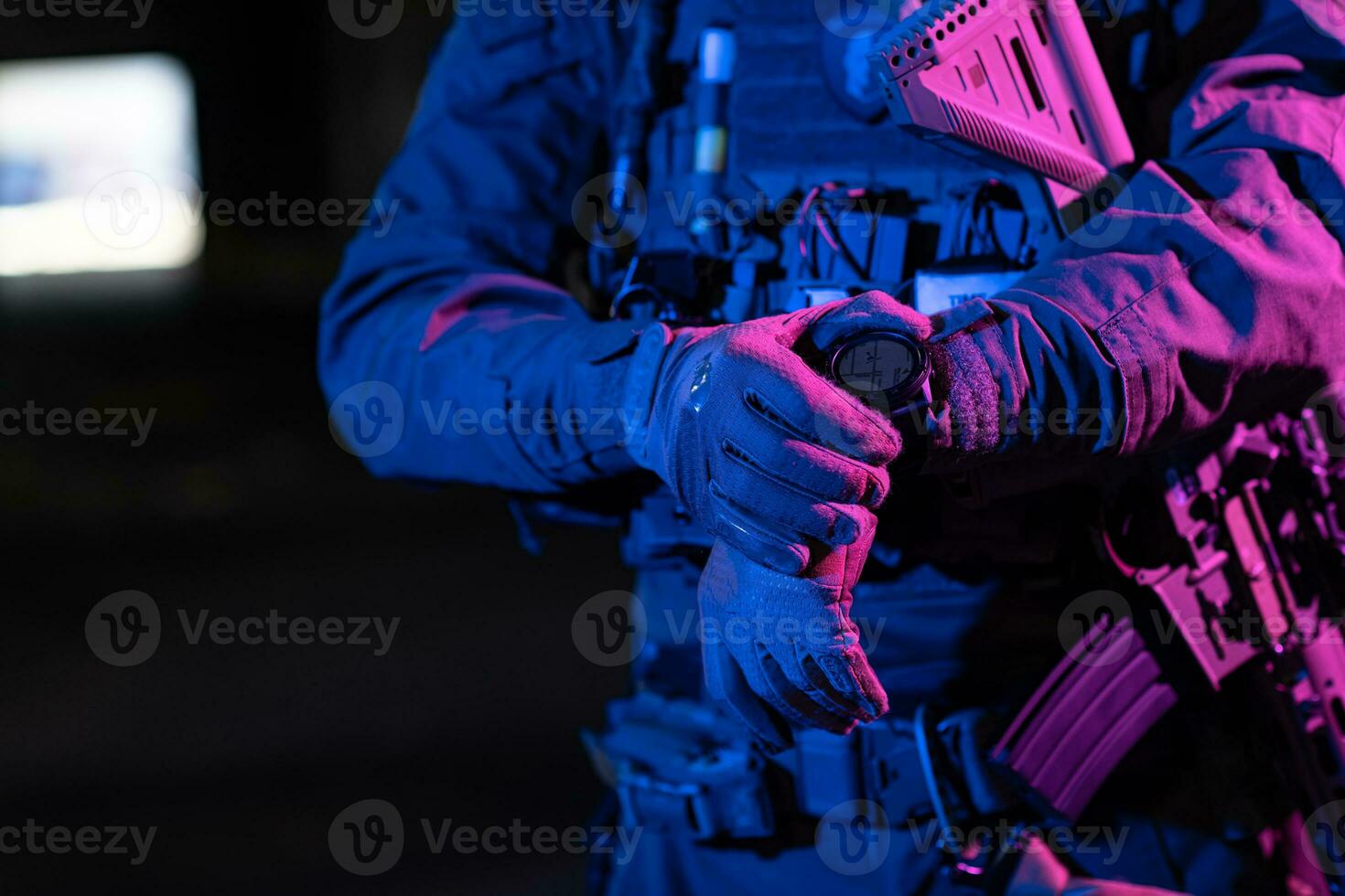 Modern warfare soldier checking navigation, time and other information on a smartwatch. Dark night black background. photo