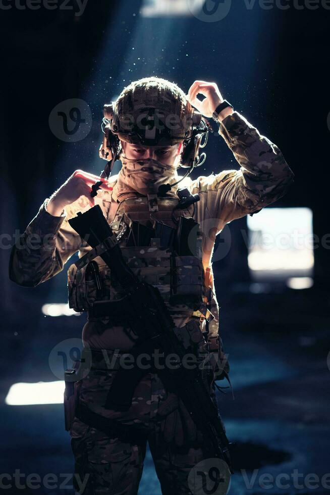 Ejército soldado en combate uniformes con un asalto rifle y combate casco noche misión oscuro antecedentes. azul y púrpura gel ligero efecto. foto