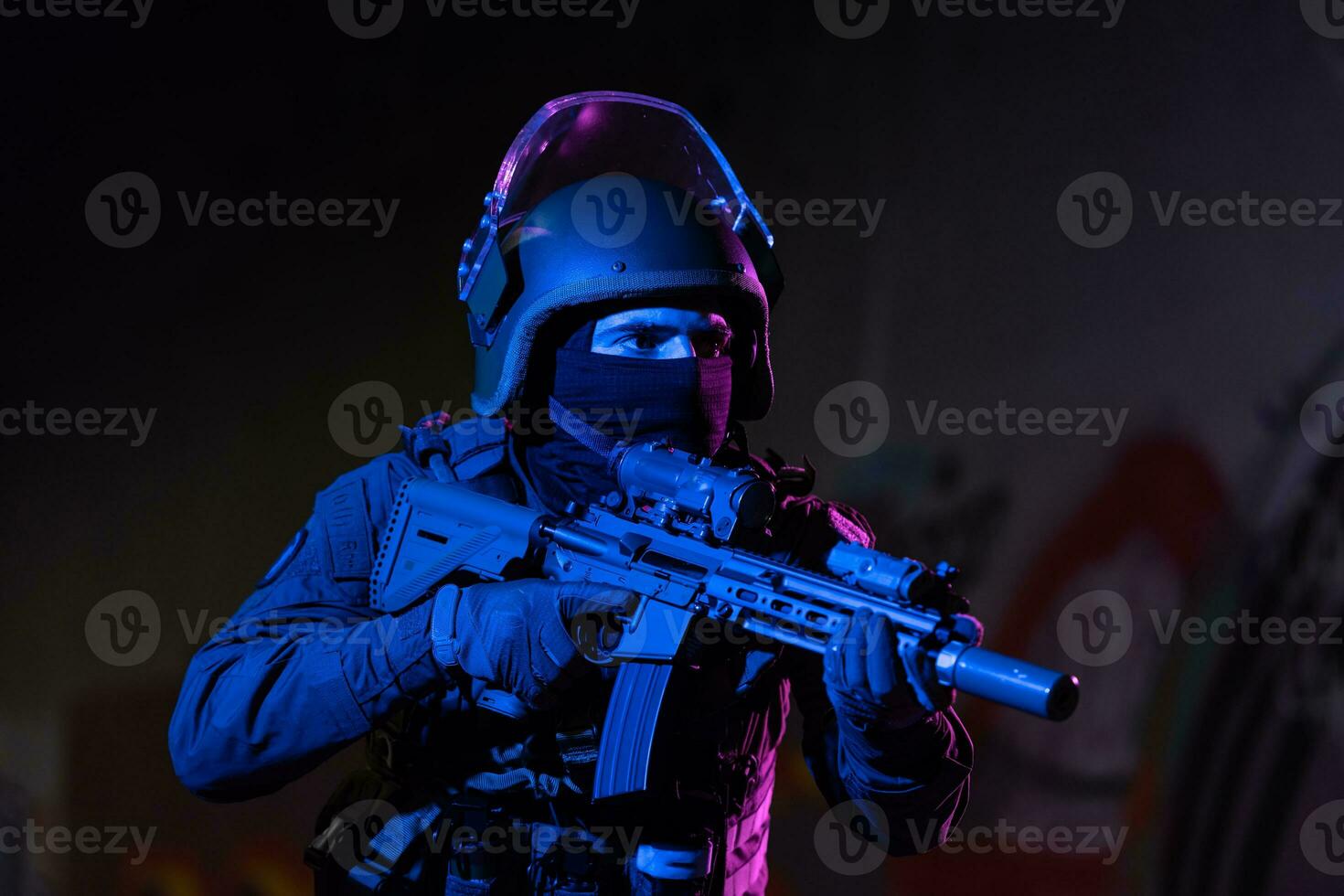 Army soldier in Combat Uniforms with an assault rifle and combat helmet night mission dark background. Blue and purple gel light effect. photo
