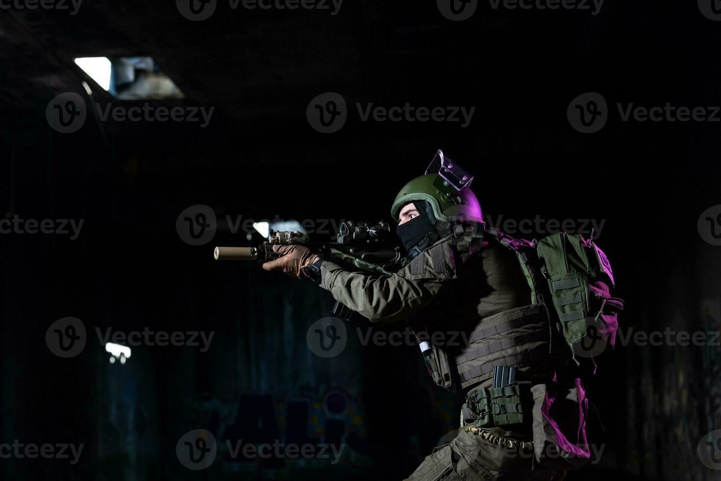 Army soldier in Combat Uniforms with an assault rifle and combat helmet night mission dark background. Blue and purple gel light effect. photo