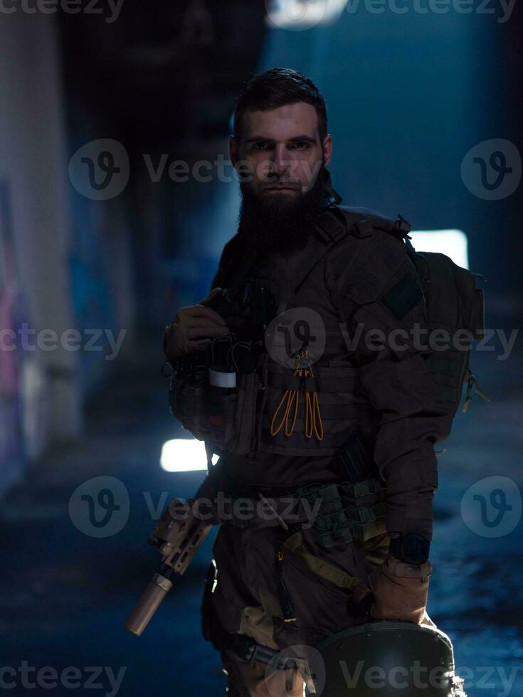 Army soldier in Combat Uniforms with an assault rifle and combat helmet night mission dark background. Blue and purple gel light effect. photo