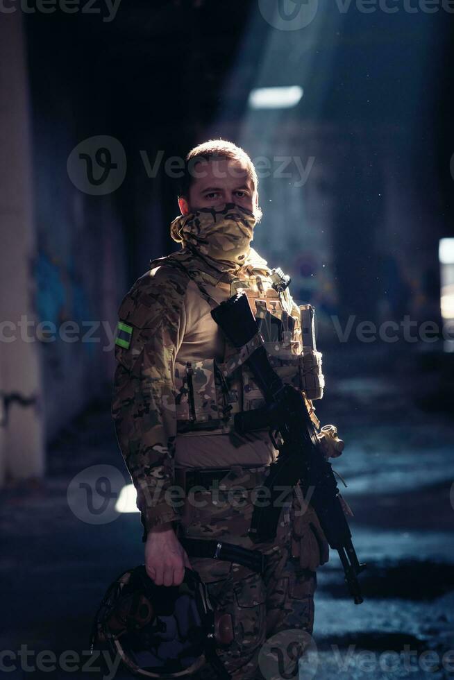 Army soldier in Combat Uniforms with an assault rifle and combat helmet night mission dark background. Blue and purple gel light effect. photo