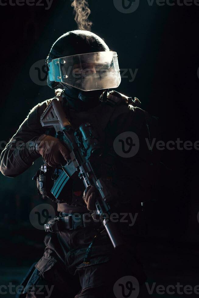 Army soldier in Combat Uniforms with an assault rifle and combat helmet night mission dark background. Blue and purple gel light effect. photo