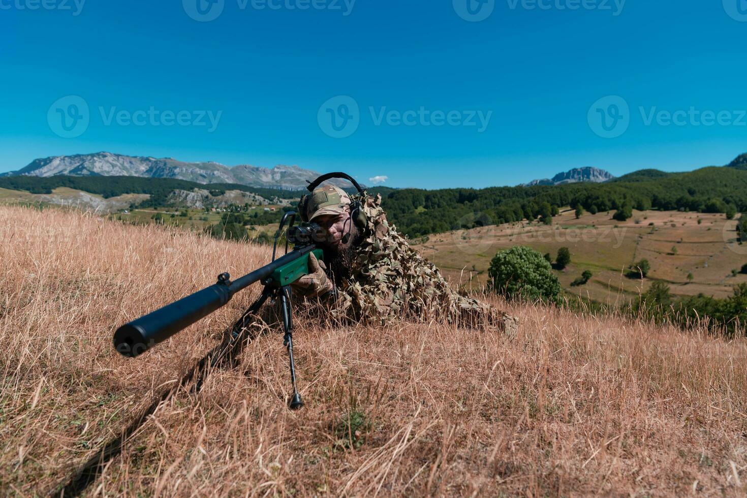 army soldier holding sniper rifle with scope and aiming in forest. war, army, technology and people concept photo