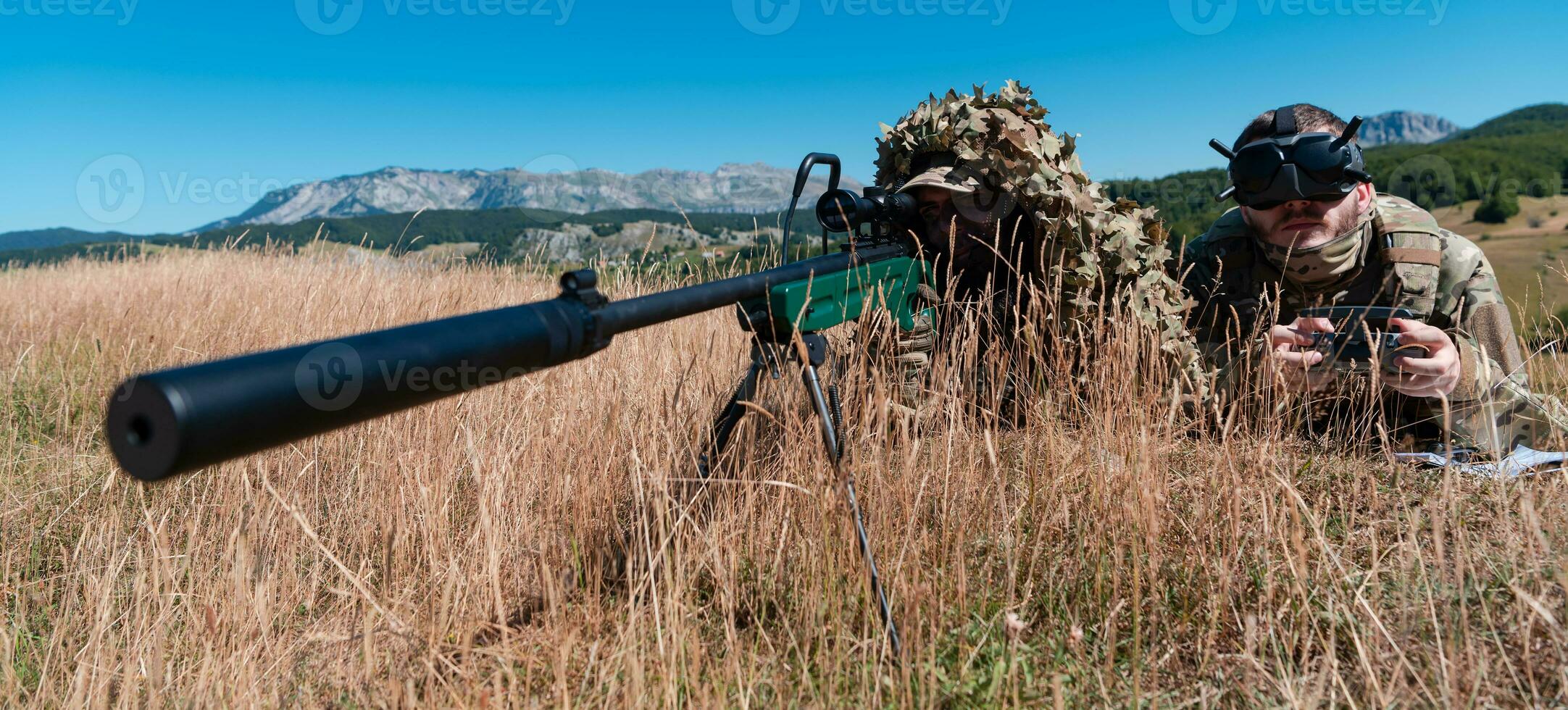 Sniper soldier assisted by an assistant to observe the area to be targeted with modern warfare tactical virtual reality goggles aerial drone military technology. photo