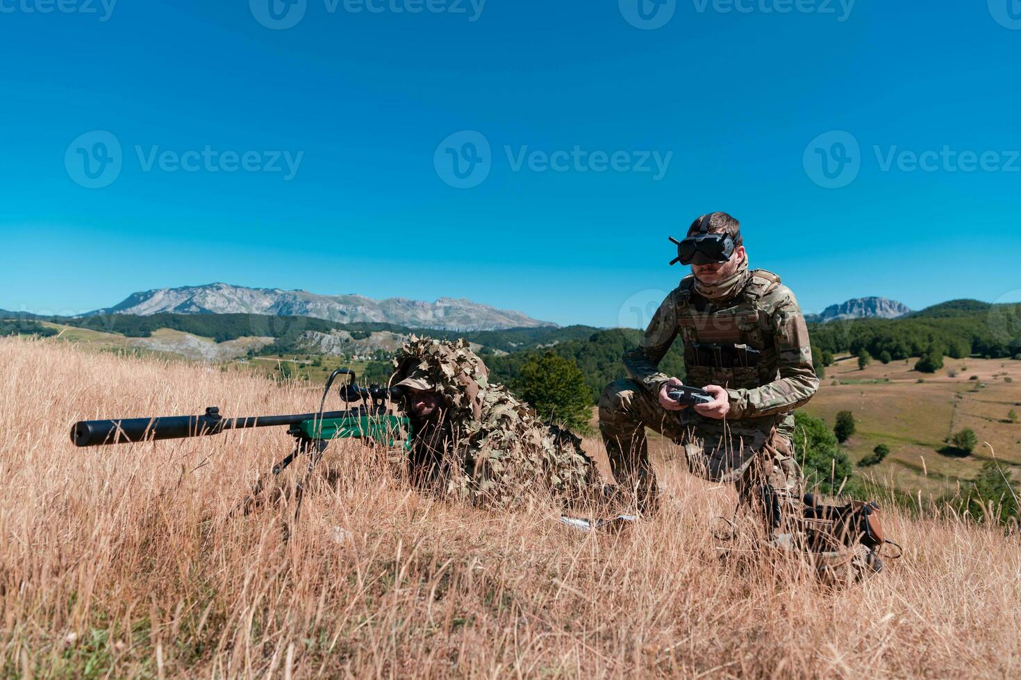 Sniper soldier assisted by an assistant to observe the area to be targeted with modern warfare tactical virtual reality goggles aerial drone military technology. photo