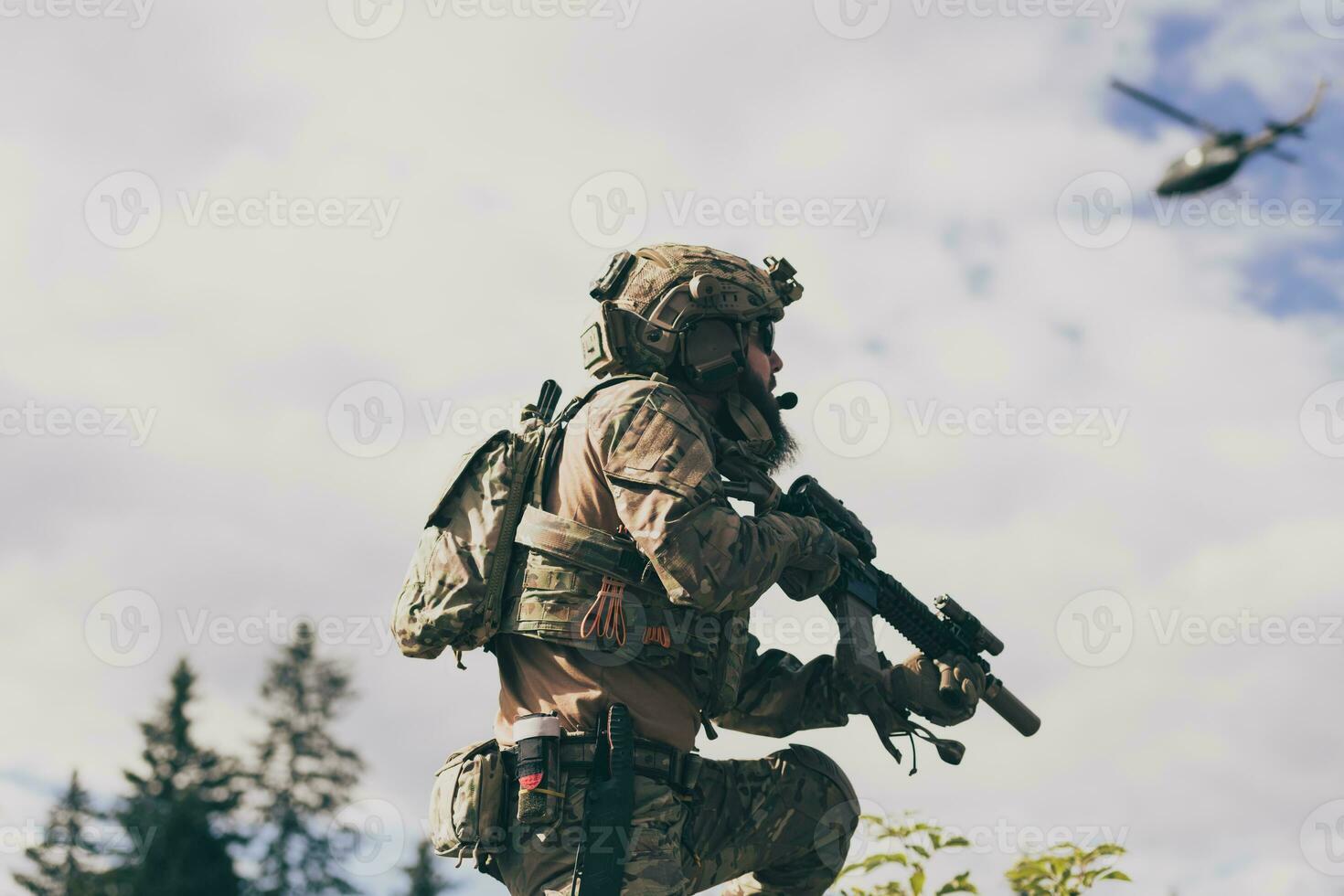 War concept. A bearded soldier in a special forces uniform fighting an enemy in a forest area. Selective focus photo