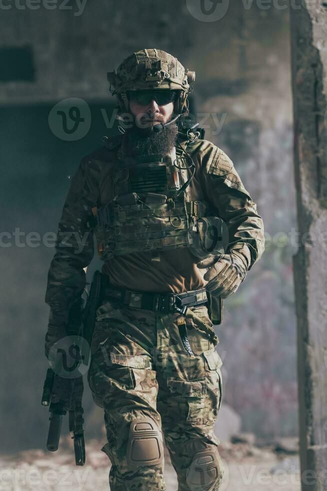 A bearded soldier in a special forces uniform walks through an abandoned building after a successful mission. Selection focus photo
