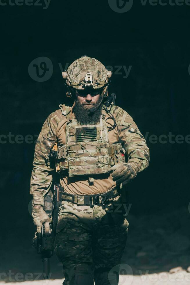 A bearded soldier in a special forces uniform walks through an abandoned building after a successful mission. Selection focus photo