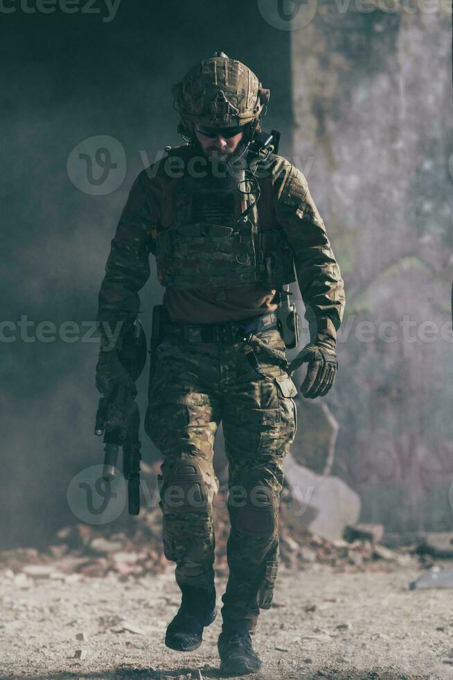 A bearded soldier in a special forces uniform walks through an abandoned building after a successful mission. Selection focus photo