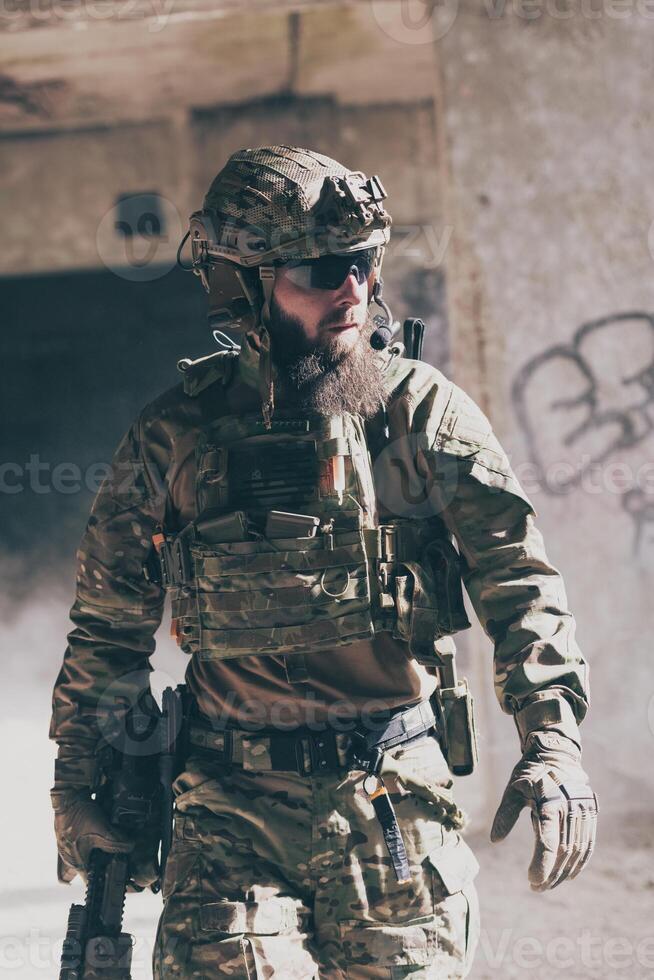A bearded soldier in a special forces uniform walks through an abandoned building after a successful mission. Selection focus photo