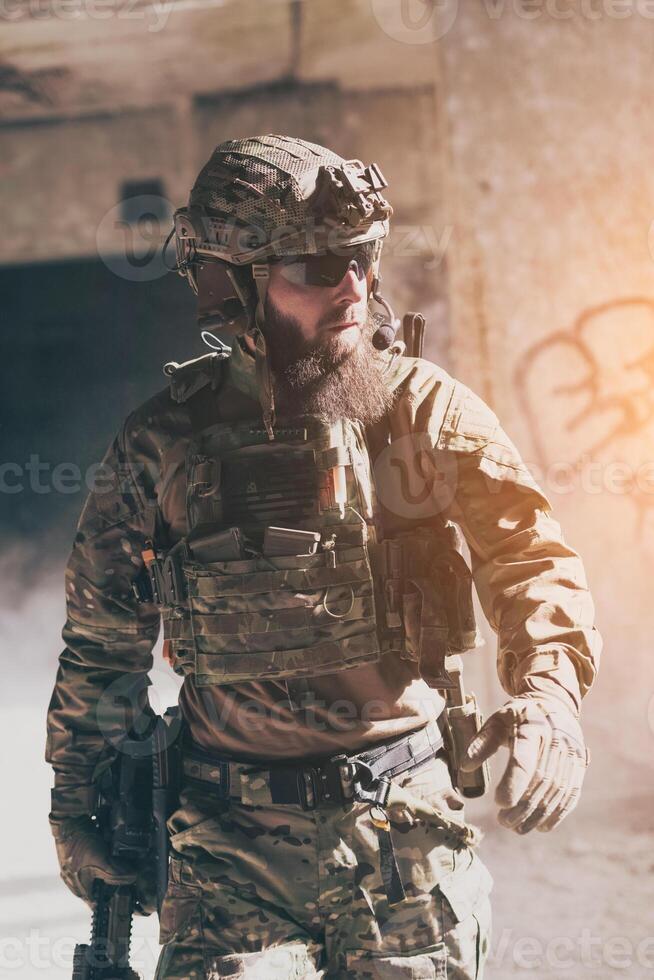 A bearded soldier in a special forces uniform walks through an abandoned building after a successful mission. Selection focus photo