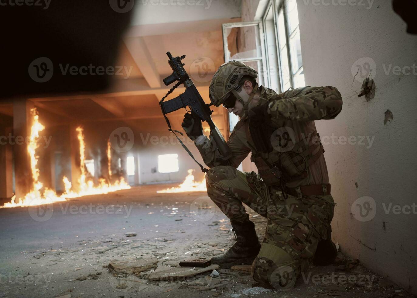 soldier in action near window changing magazine and take cover photo