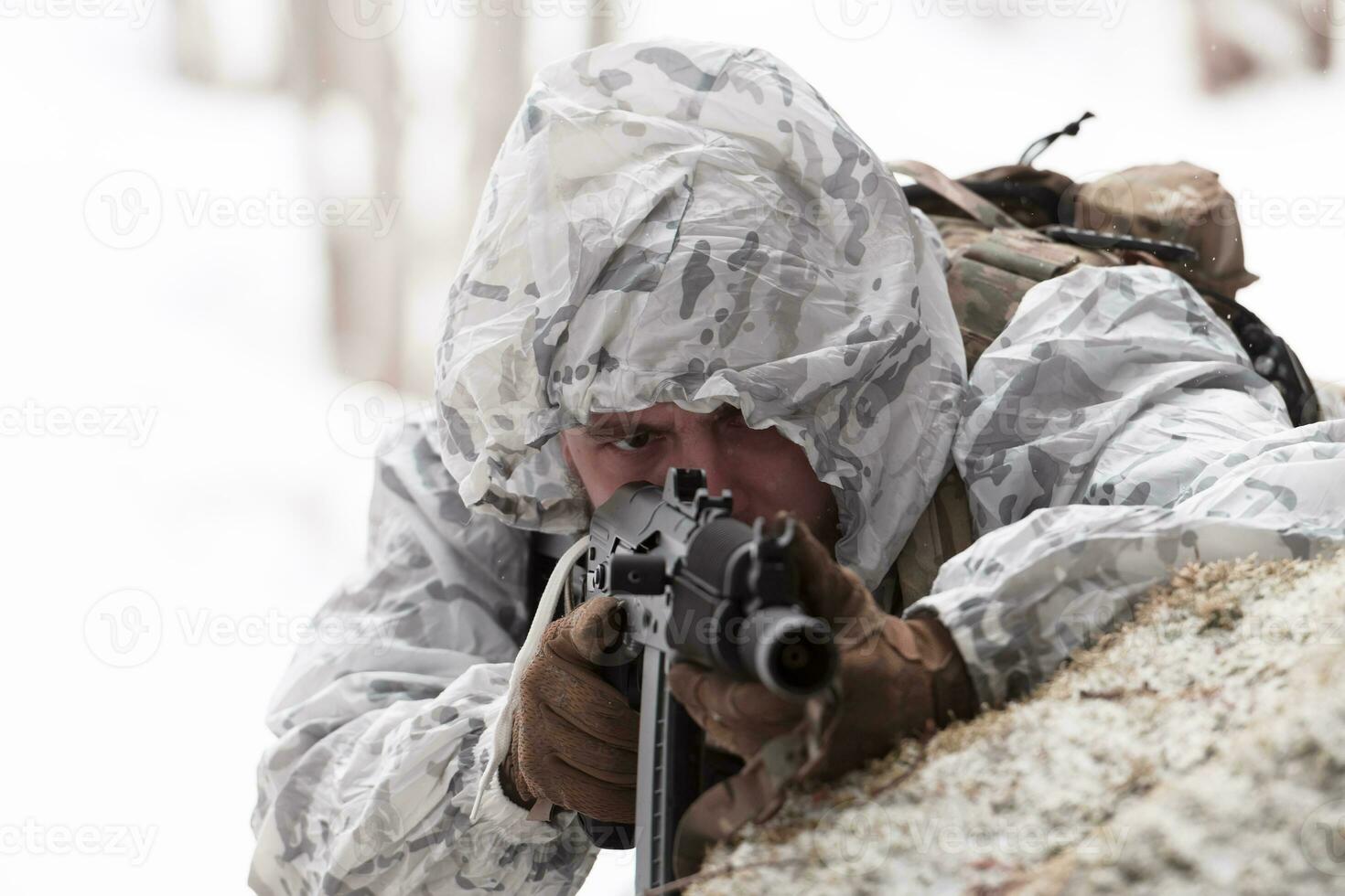 guerra de invierno en las montañas árticas. operación en condiciones frías. soldado en uniforme camuflado de invierno en el ejército de guerra moderno en un día de nieve en el campo de batalla del bosque con un rifle. enfoque selectivo foto