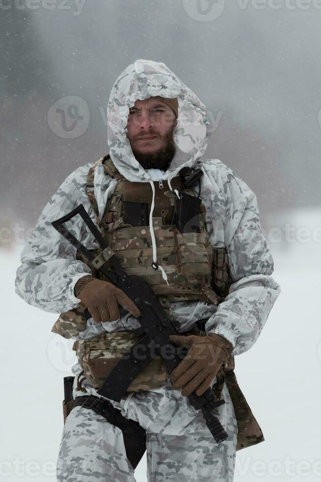 Winter war in the Arctic mountains. Operation in cold conditions.Soldier in winter camouflaged uniform in Modern warfare army on a snow day on forest battlefield with a rifle. Selective focus photo