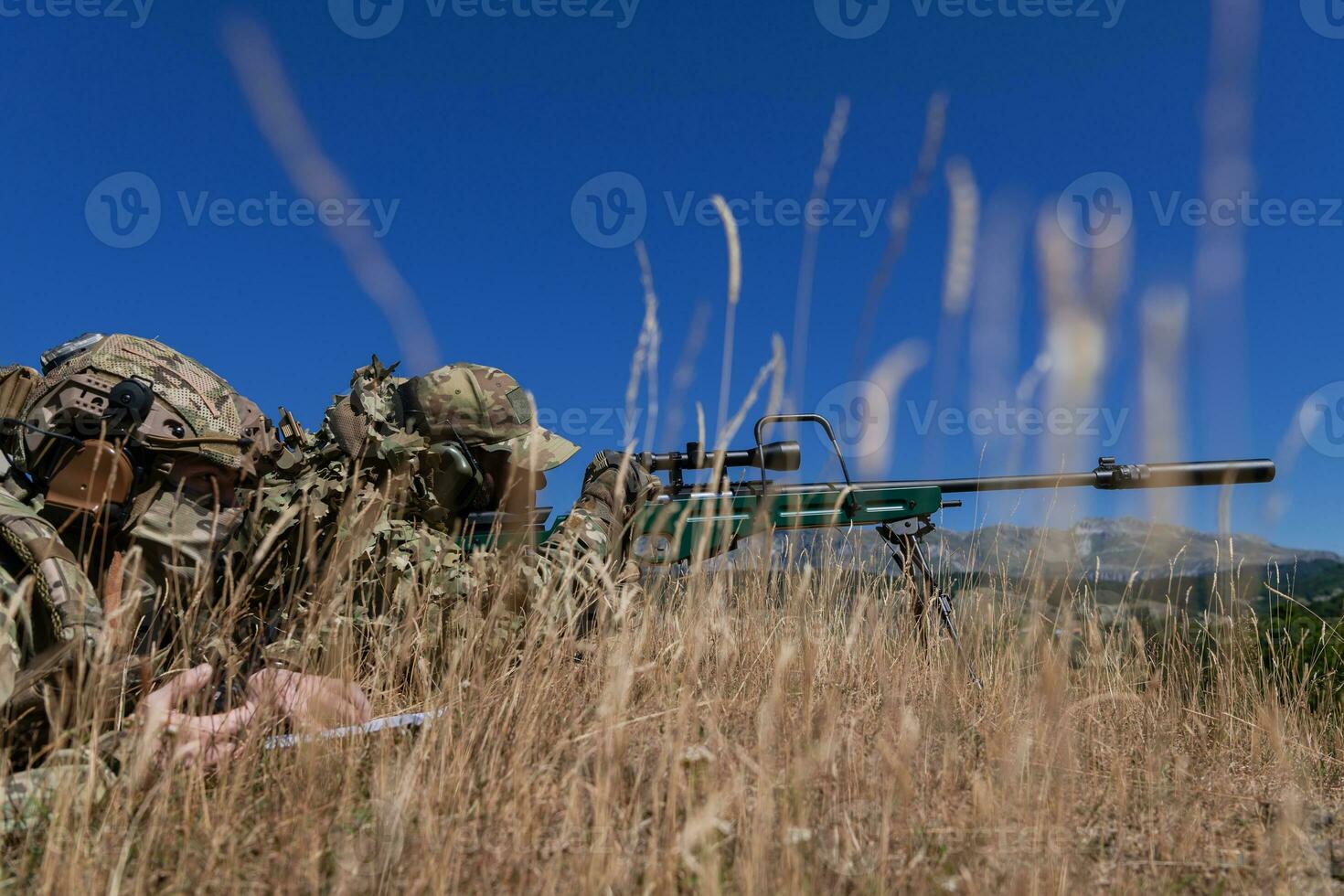 Sniper soldier assisted by an assistant to observe the area to be targeted with modern warfare tactical virtual reality goggles aerial drone military technology. photo