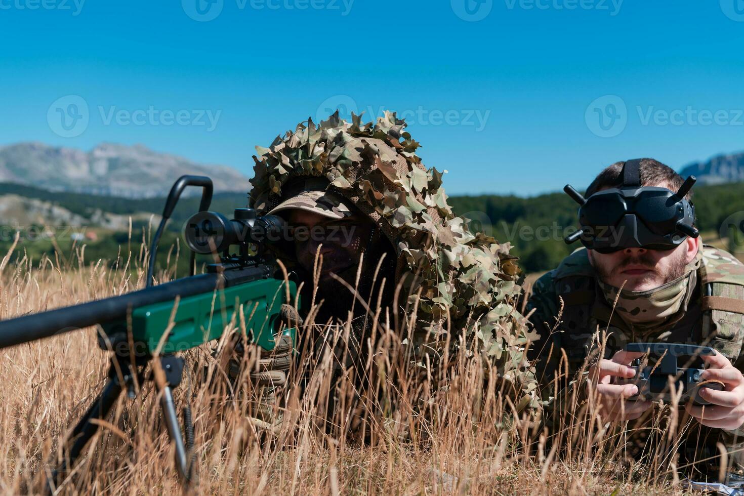 Sniper soldier assisted by an assistant to observe the area to be targeted with modern warfare tactical virtual reality goggles aerial drone military technology. photo