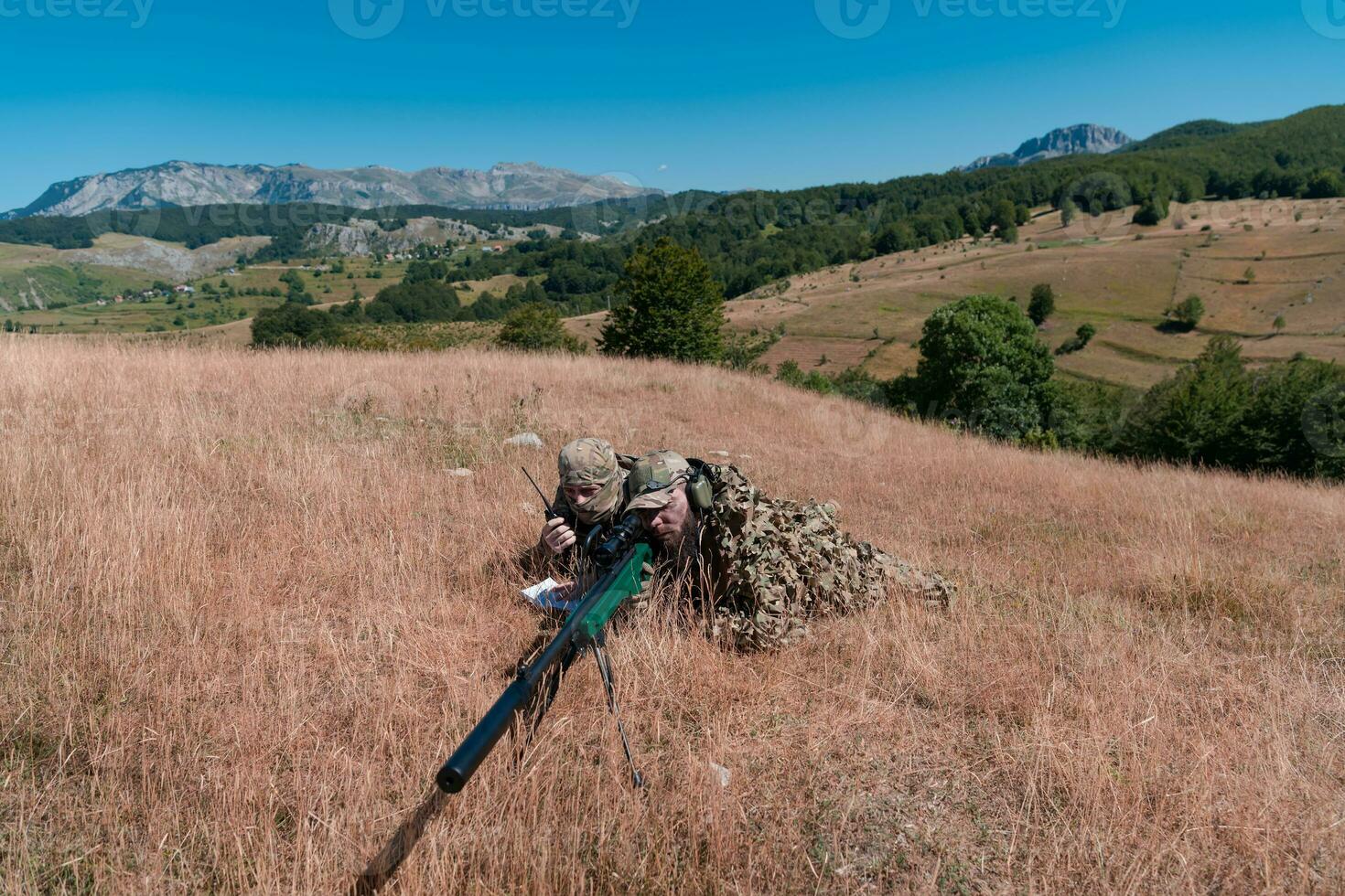 Sniper soldier assisted by an assistant to observe the area to be targeted with modern warfare tactical virtual reality goggles aerial drone military technology. photo