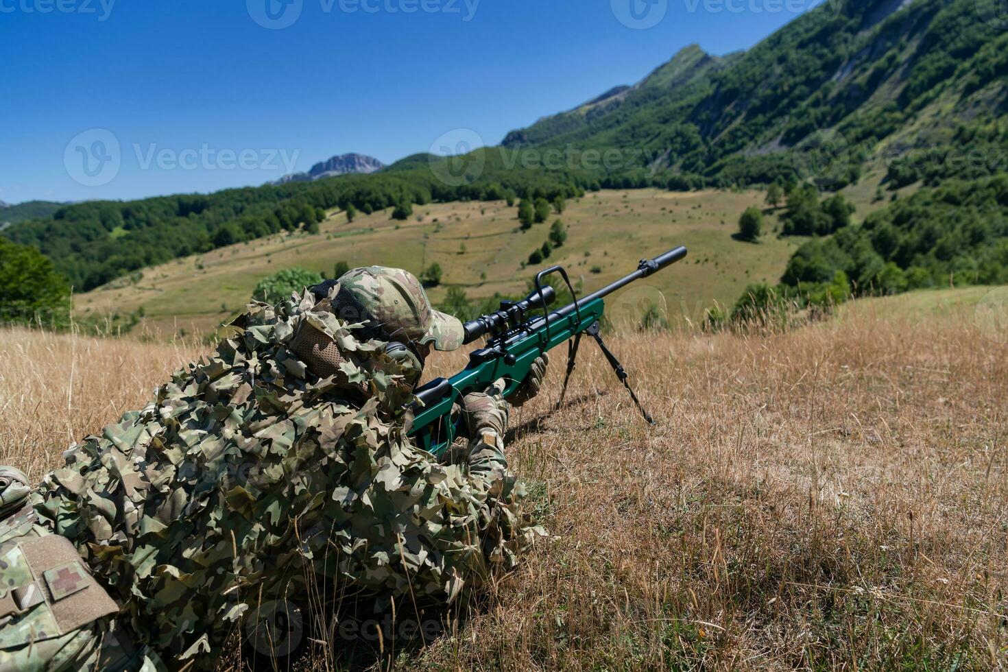 army soldier holding sniper rifle with scope and aiming in forest. war, army, technology and people concept photo