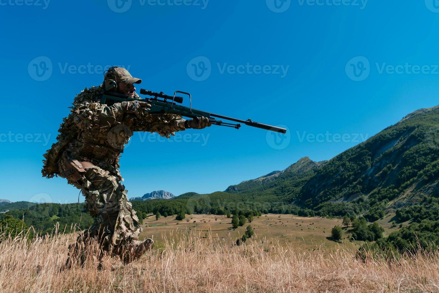 army soldier holding sniper rifle with scope and aiming in forest. war, army, technology and people concept photo