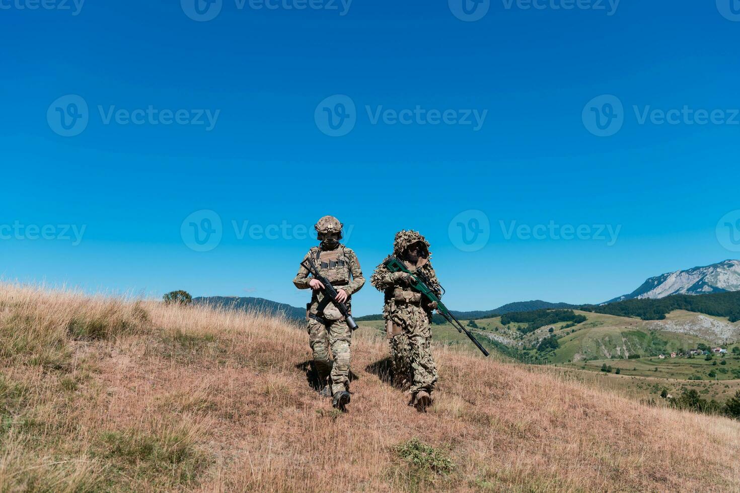 un francotirador equipo equipo de soldados es yendo clandestino. francotirador asistente y equipo líder caminando y puntería en naturaleza con amarillo césped y azul cielo. táctico camuflaje uniforme. foto