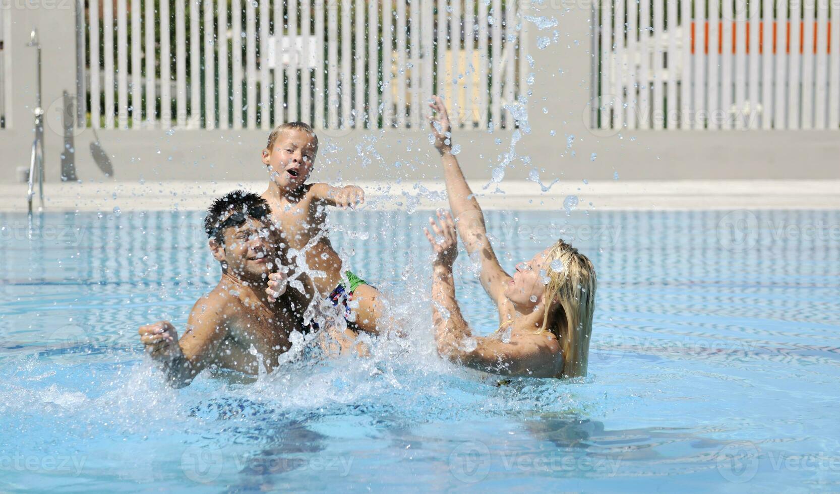 familia joven feliz divertirse en la piscina foto