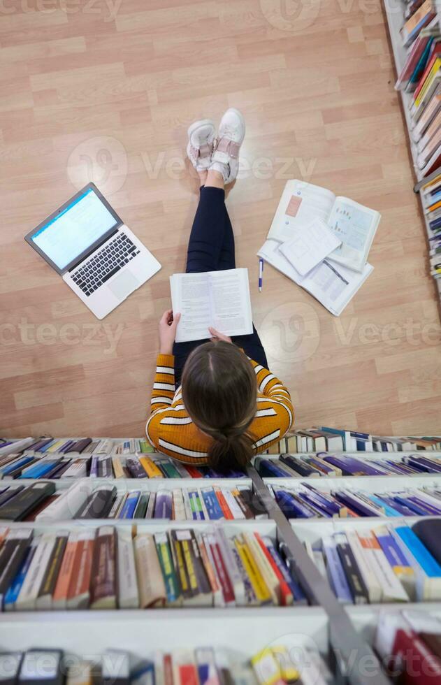 the student uses a notebook and a school library photo