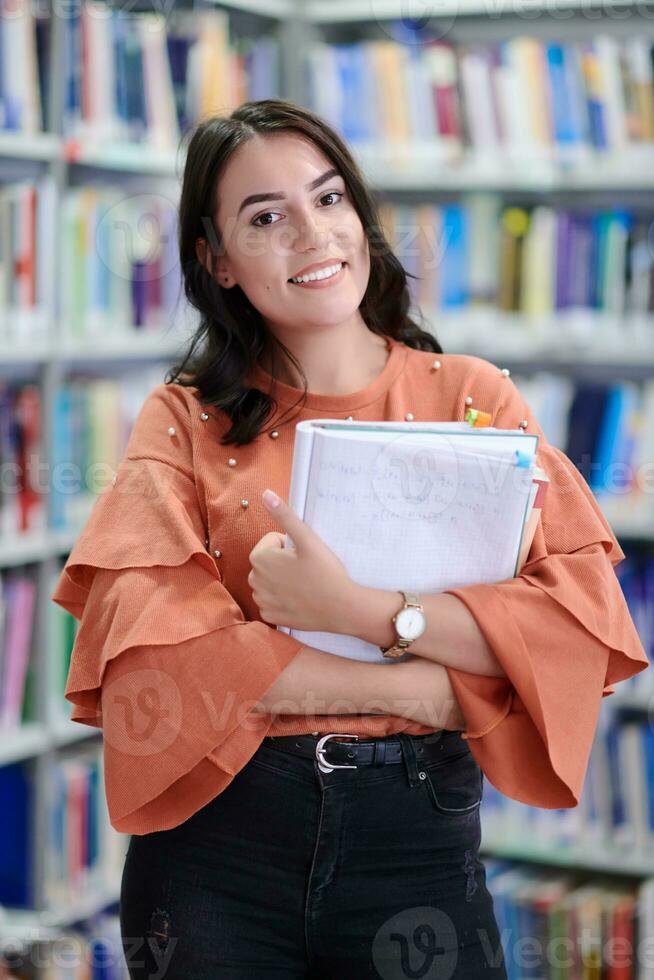 the student uses a notebook and a school library photo