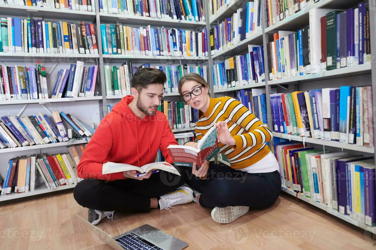 the students uses a notebook, laptop and a school library photo