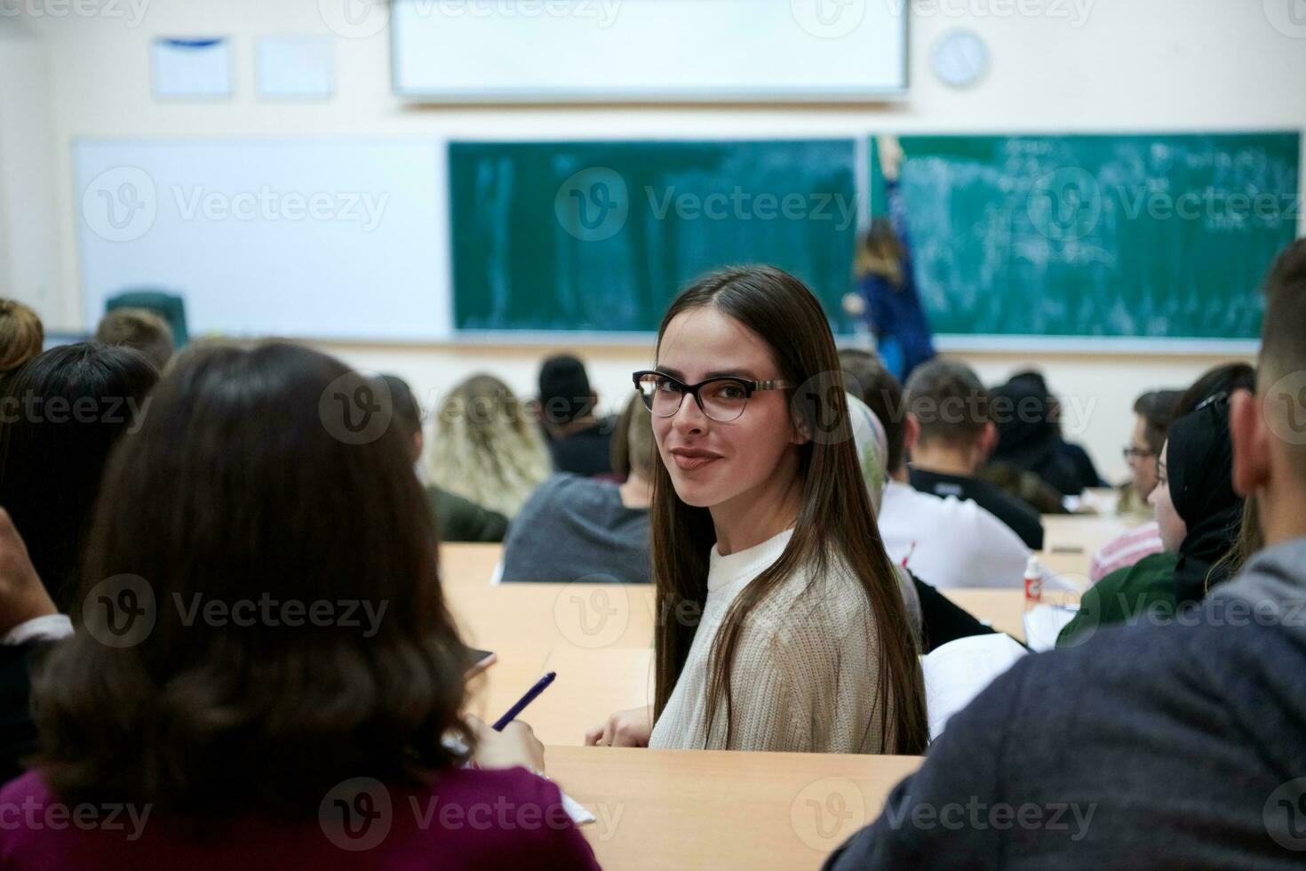 girl sitting in an amphitheater and talking to her colleagues photo