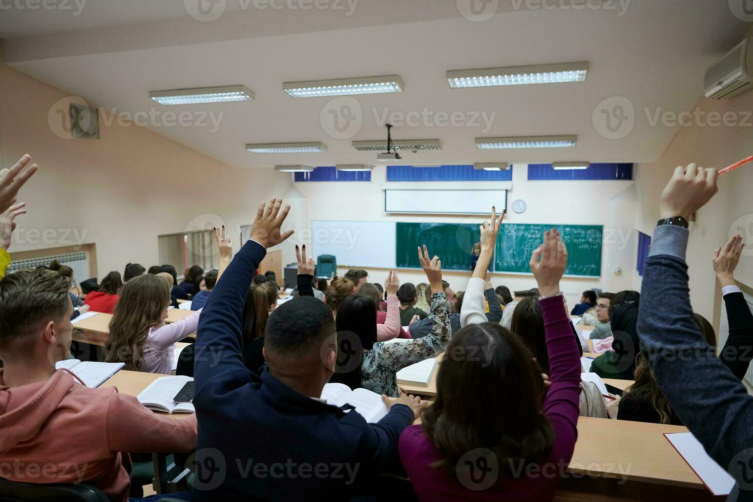 manos y brazos levantados de un gran grupo de personas en la sala de clase foto