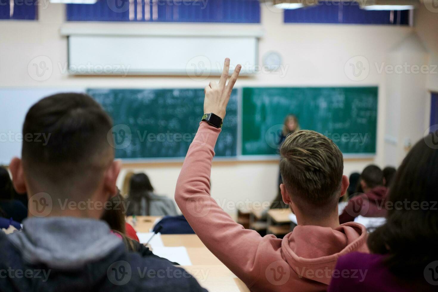 The student raises his hands asking a question in class in college photo