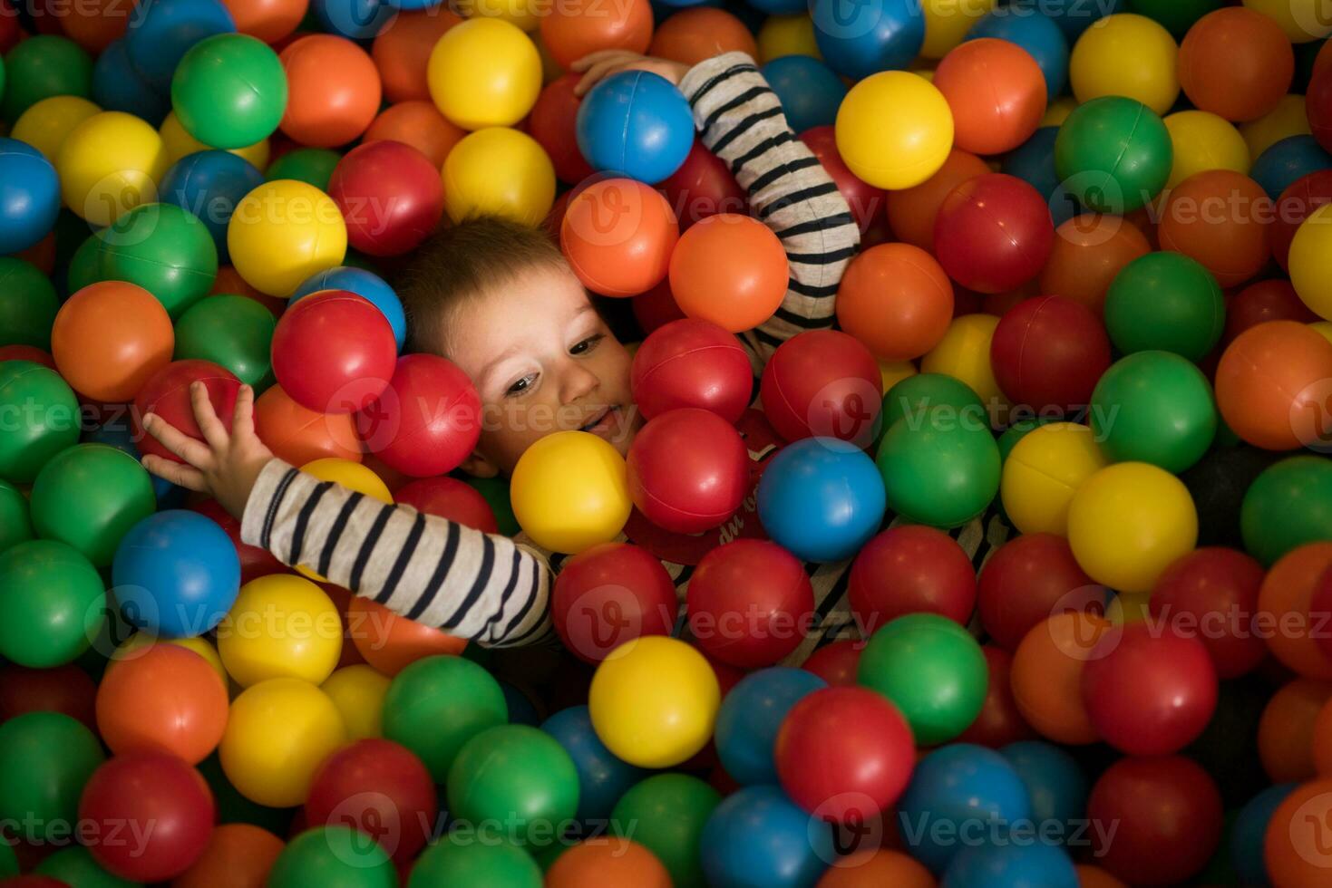 boy having fun in hundreds of colorful plastic balls photo