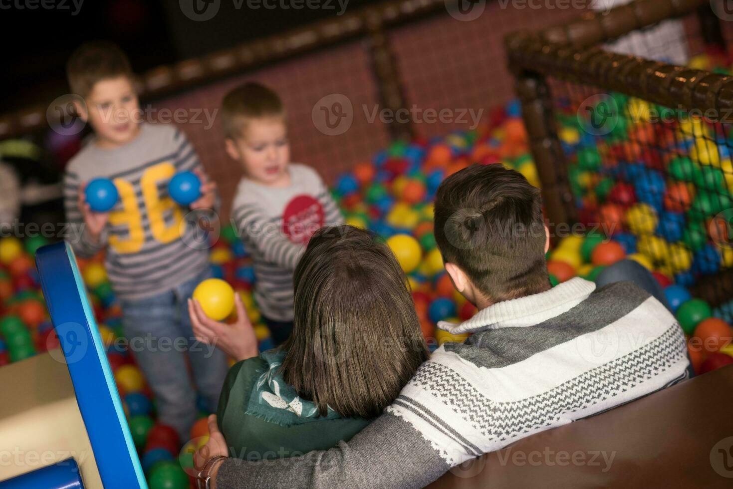 padres jóvenes con hijos en una sala de juegos para niños foto