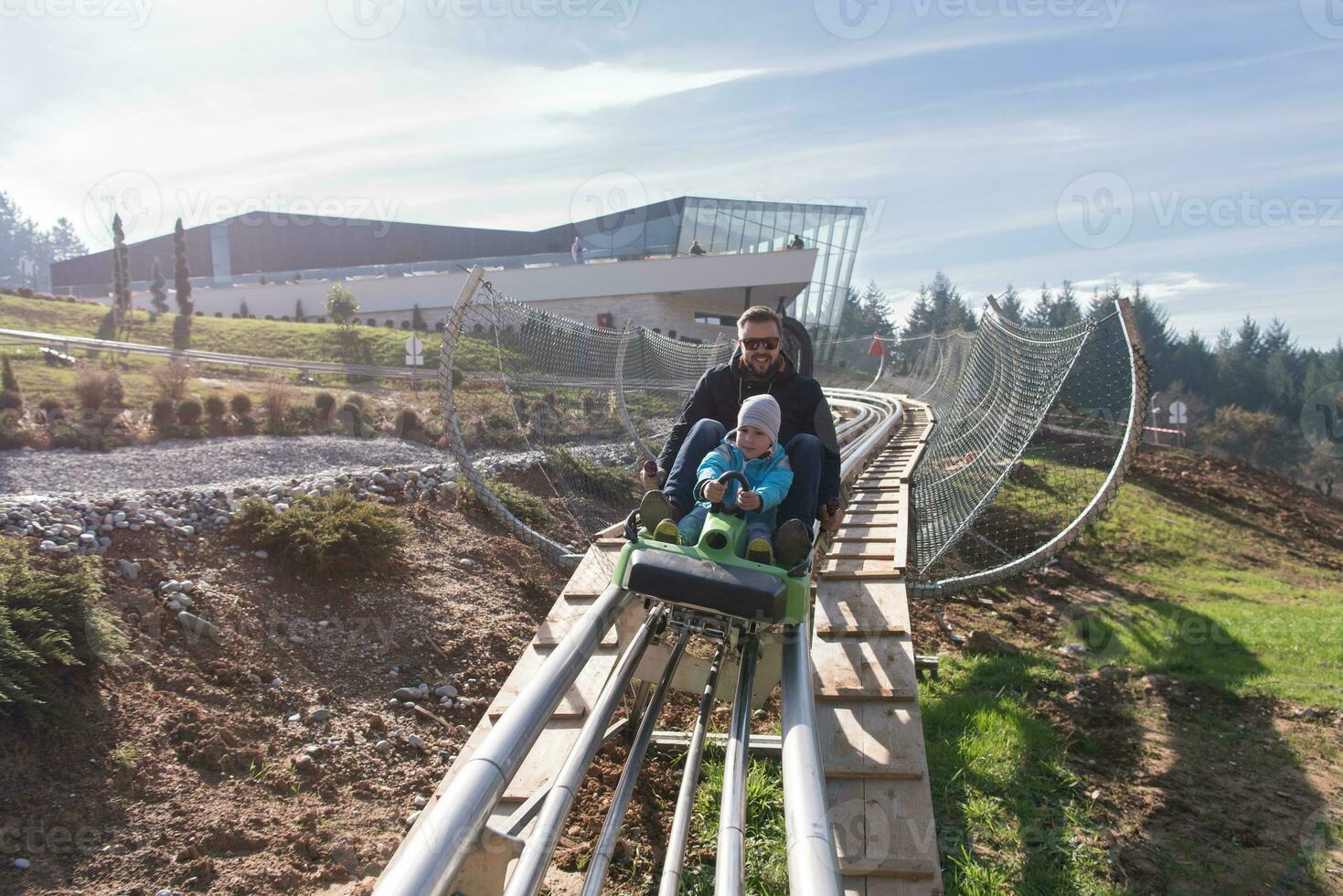 father and son enjoys driving on alpine coaster photo