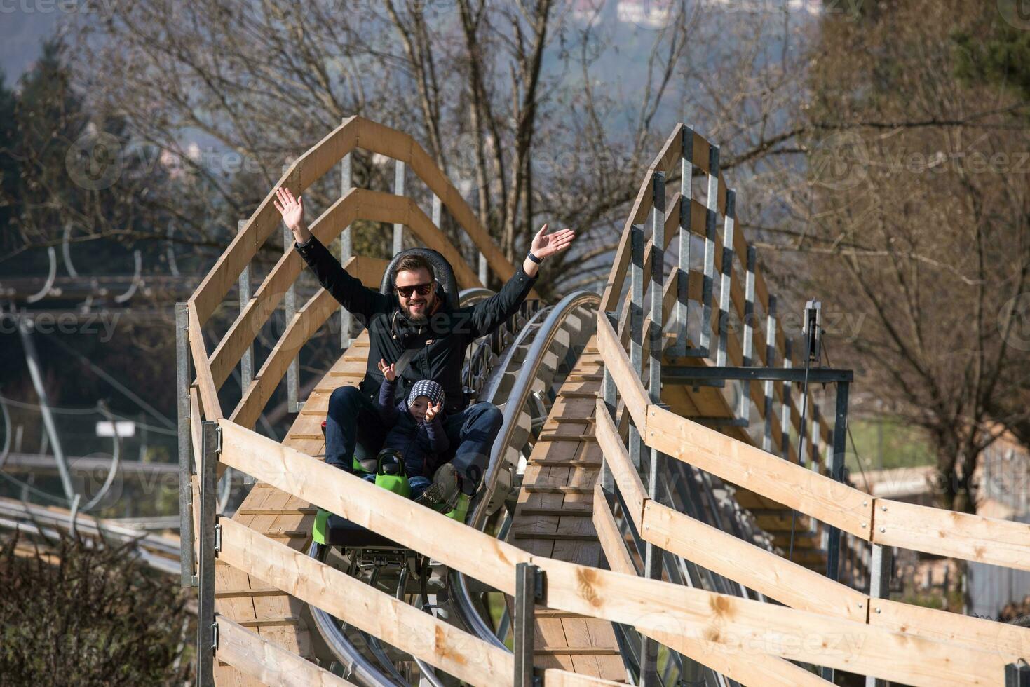 father and son enjoys driving on alpine coaster photo