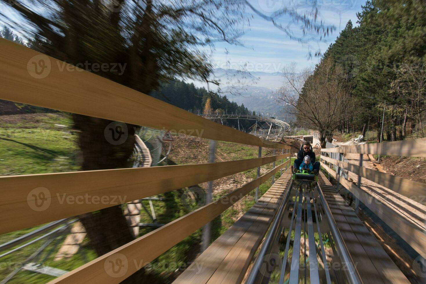 father and son enjoys driving on alpine coaster photo