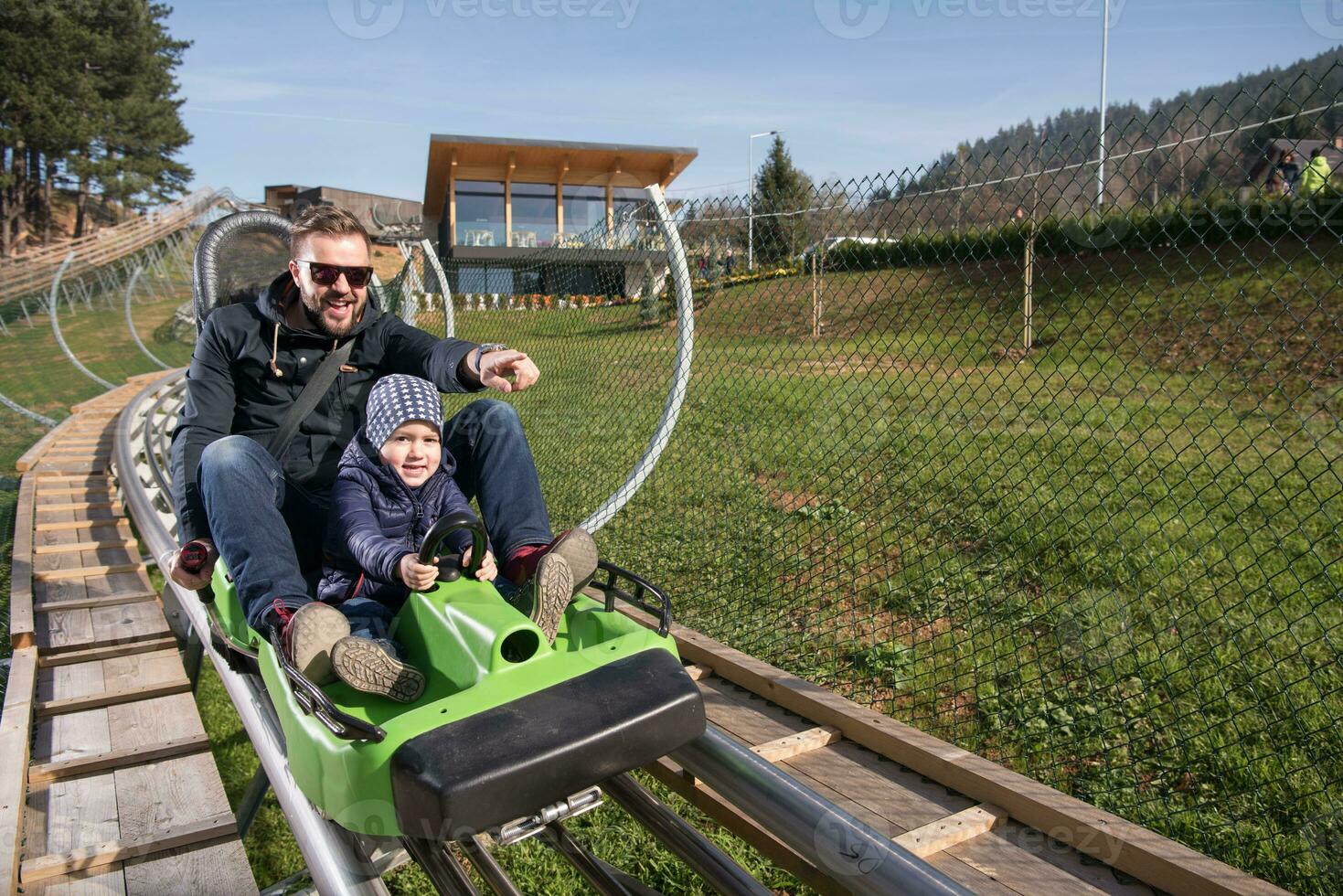 father and son enjoys driving on alpine coaster photo