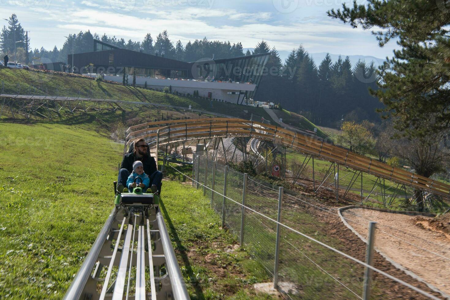 father and son enjoys driving on alpine coaster photo