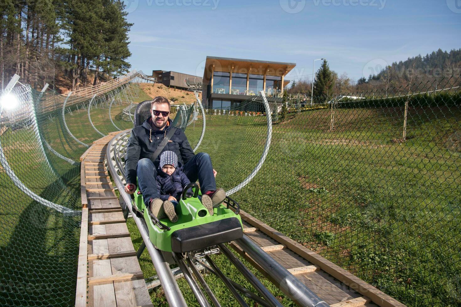 father and son enjoys driving on alpine coaster photo