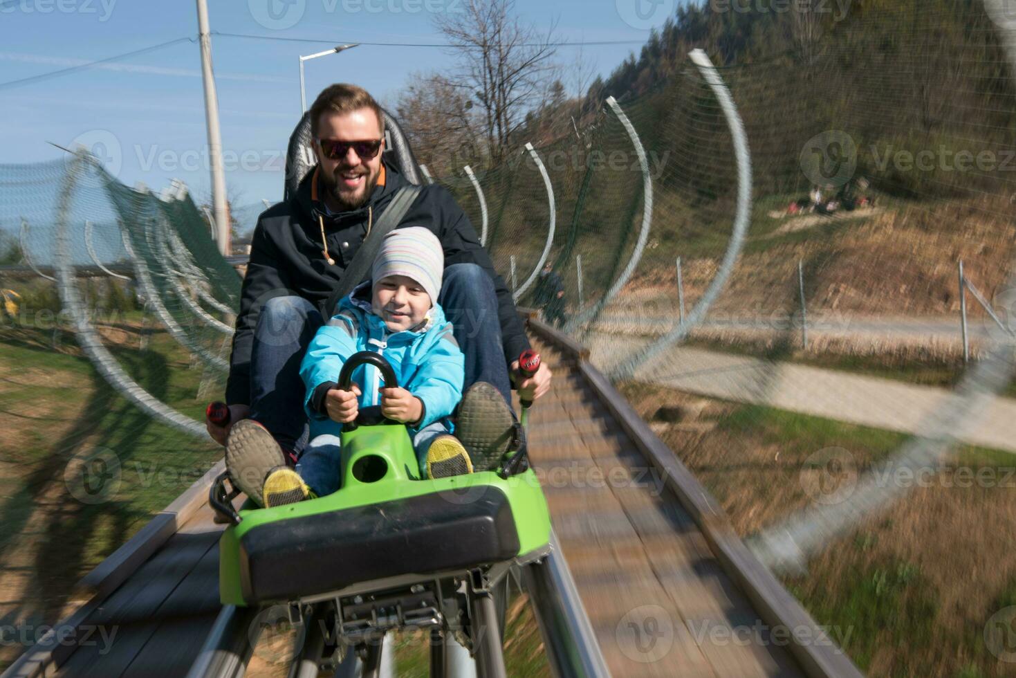 father and son enjoys driving on alpine coaster photo