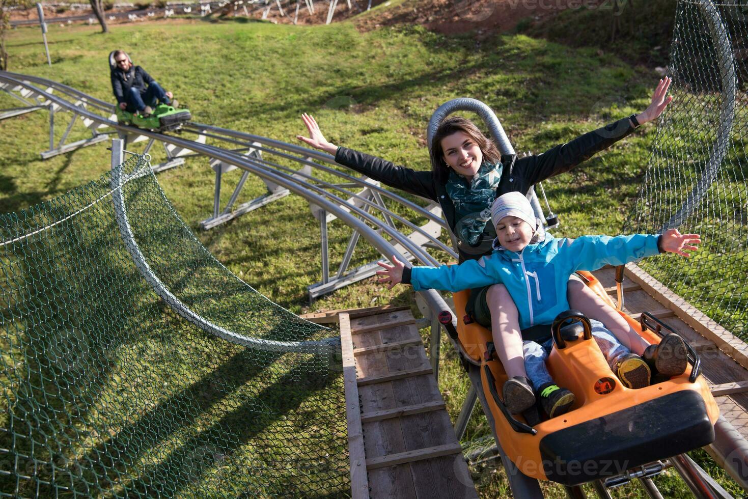 madre e hijo disfrutan conduciendo en una montaña rusa alpina foto