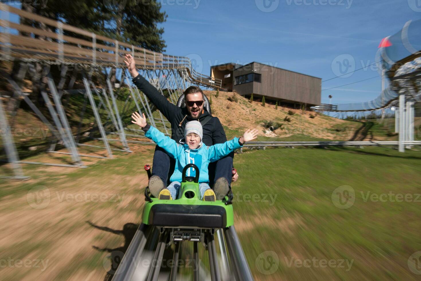 father and son enjoys driving on alpine coaster photo