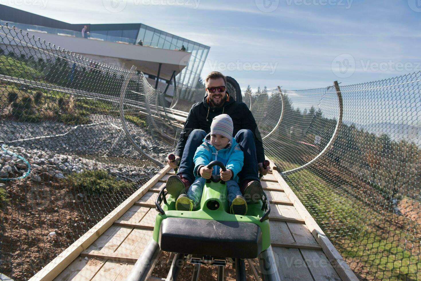 father and son enjoys driving on alpine coaster photo