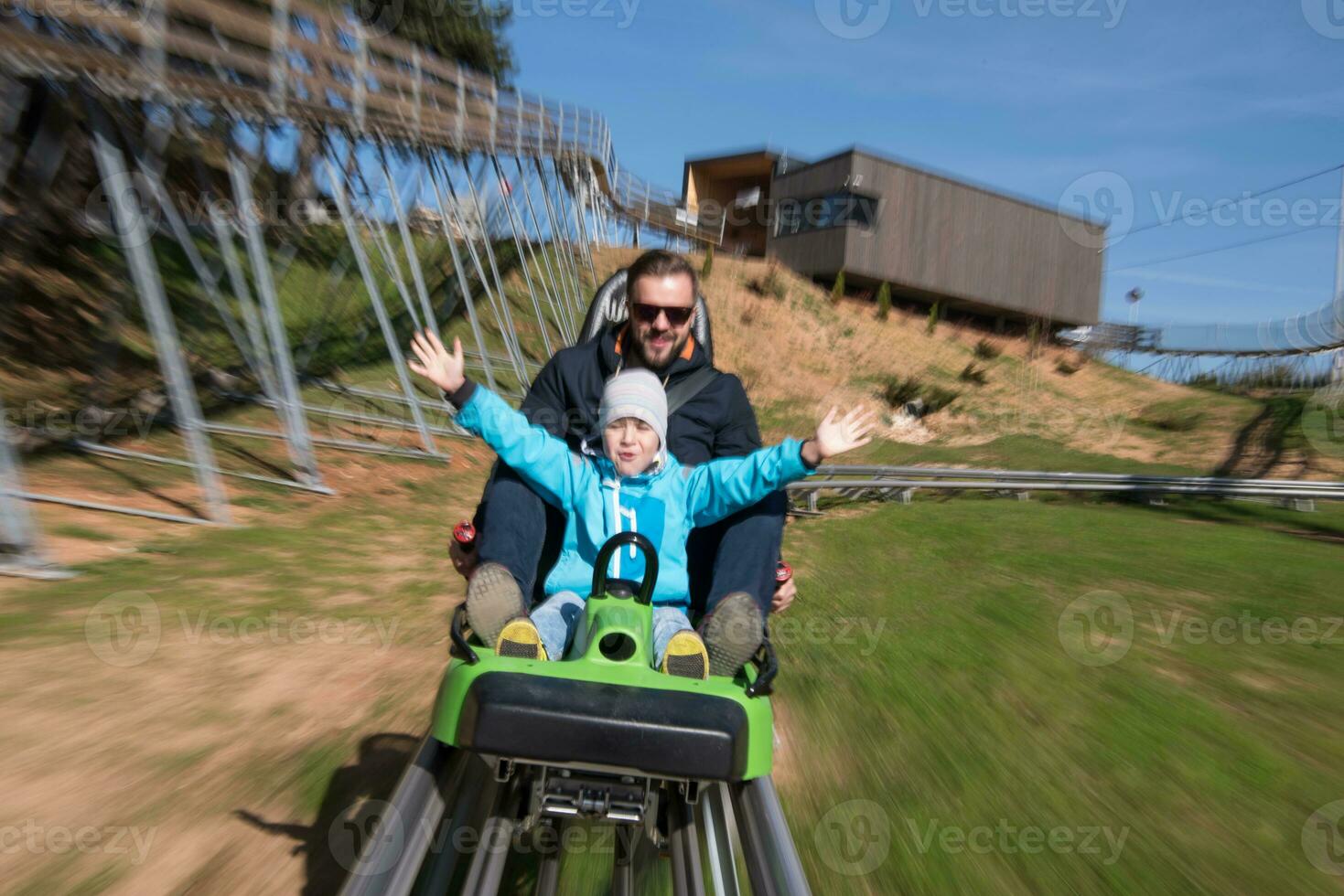 father and son enjoys driving on alpine coaster photo